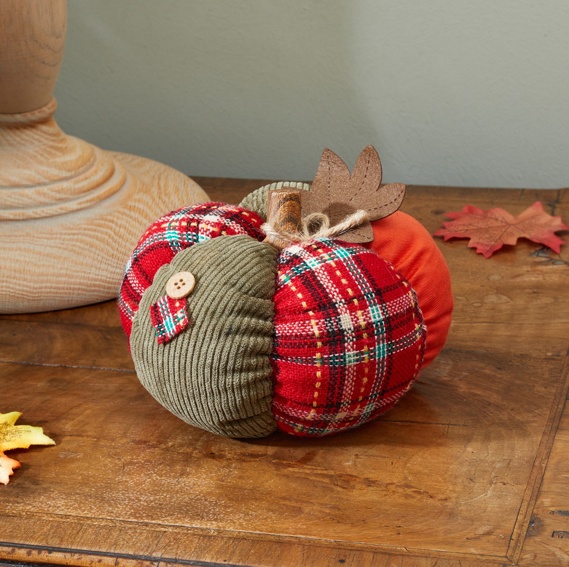 Decorative pumpkins with plaid patterns and wooden buttons on a wooden surface.