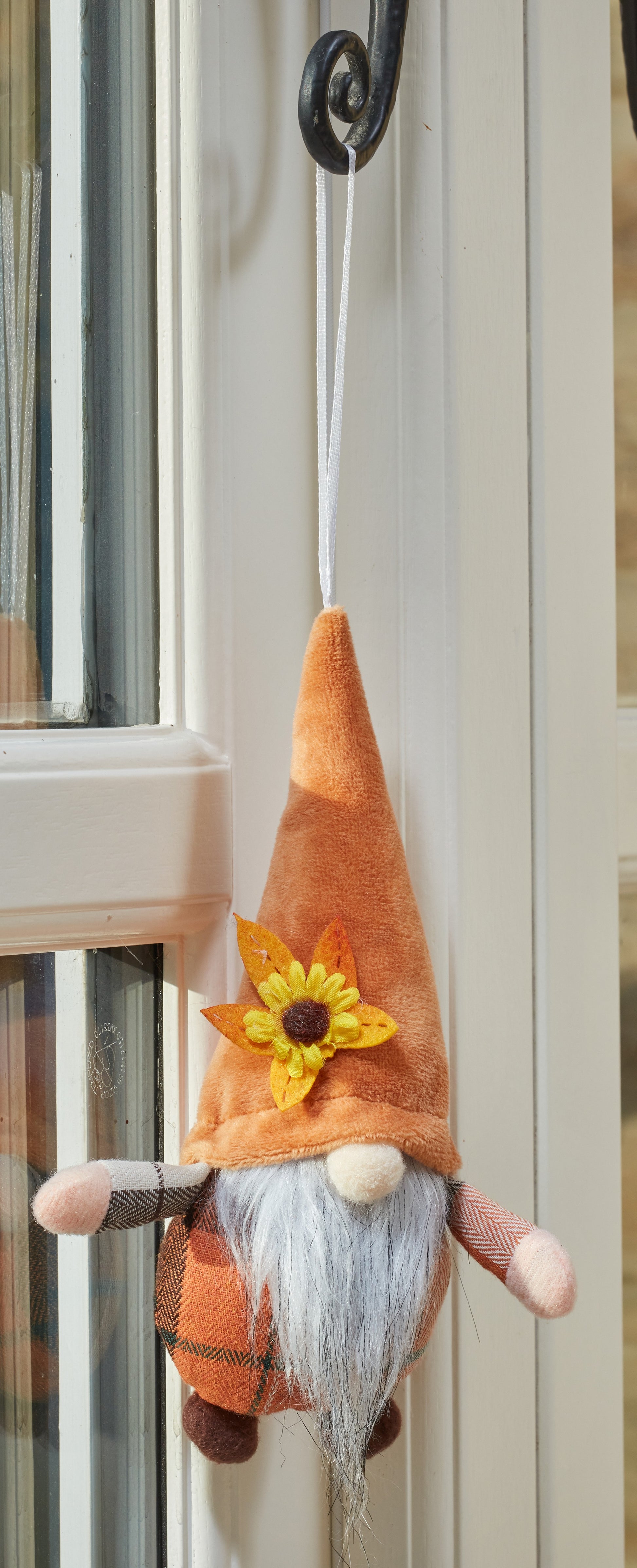 Decorative gnome with an orange hat and sunflower, hanging on a door.