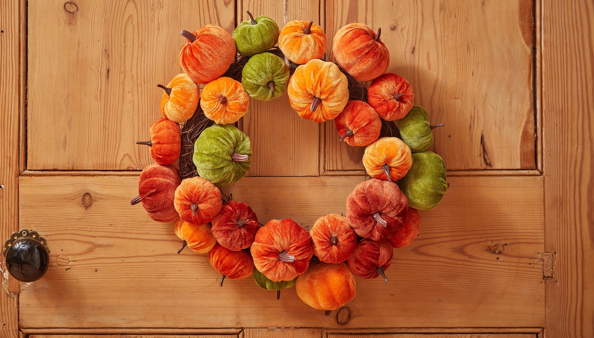 Decorative wreath with pumpkins on a wooden door