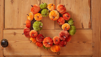 Decorative wreath with pumpkins on a wooden door