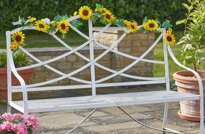 White metal bench with sunflower decorations in a garden setting