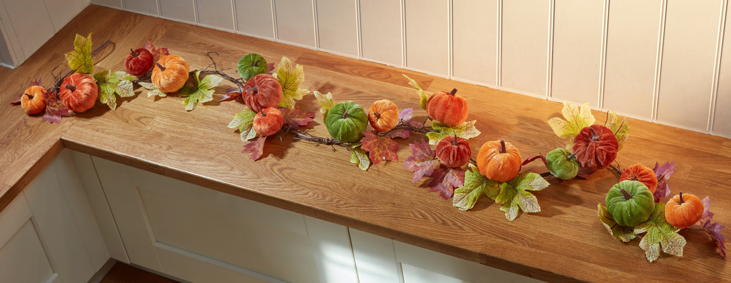 Decorative fall arrangement of pumpkins and leaves on a wooden surface.