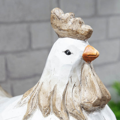 Decorative chicken statue with a crown against a gray brick wall.