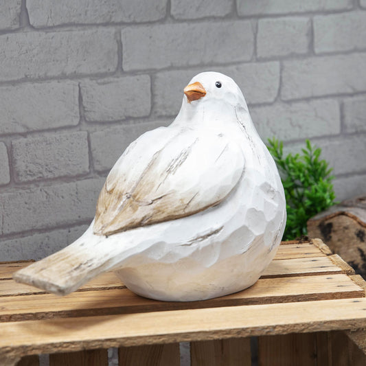 Decorative white bird sculpture on a wooden surface with a brick wall background