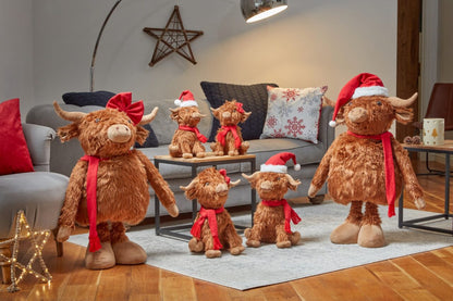 Group of Highland cow plush toys wearing Santa hats and scarves in a living room setting.