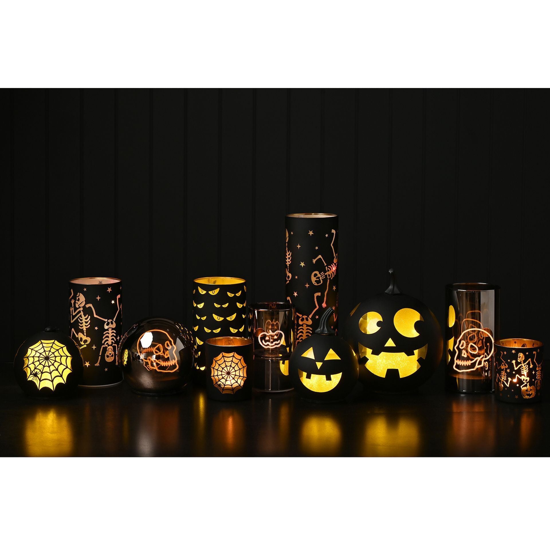 Collection of Halloween-themed decorative items including candles and a pumpkin on a dark background