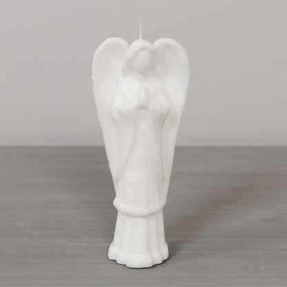 White angel-shaped candle on a gray surface with a neutral background
