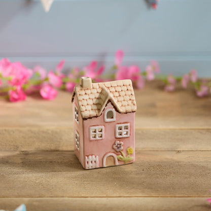 Pink ceramic miniature house ornament | Decorative cottage figurine with tan roof and floral detail in a garden setting | UK home or garden décor