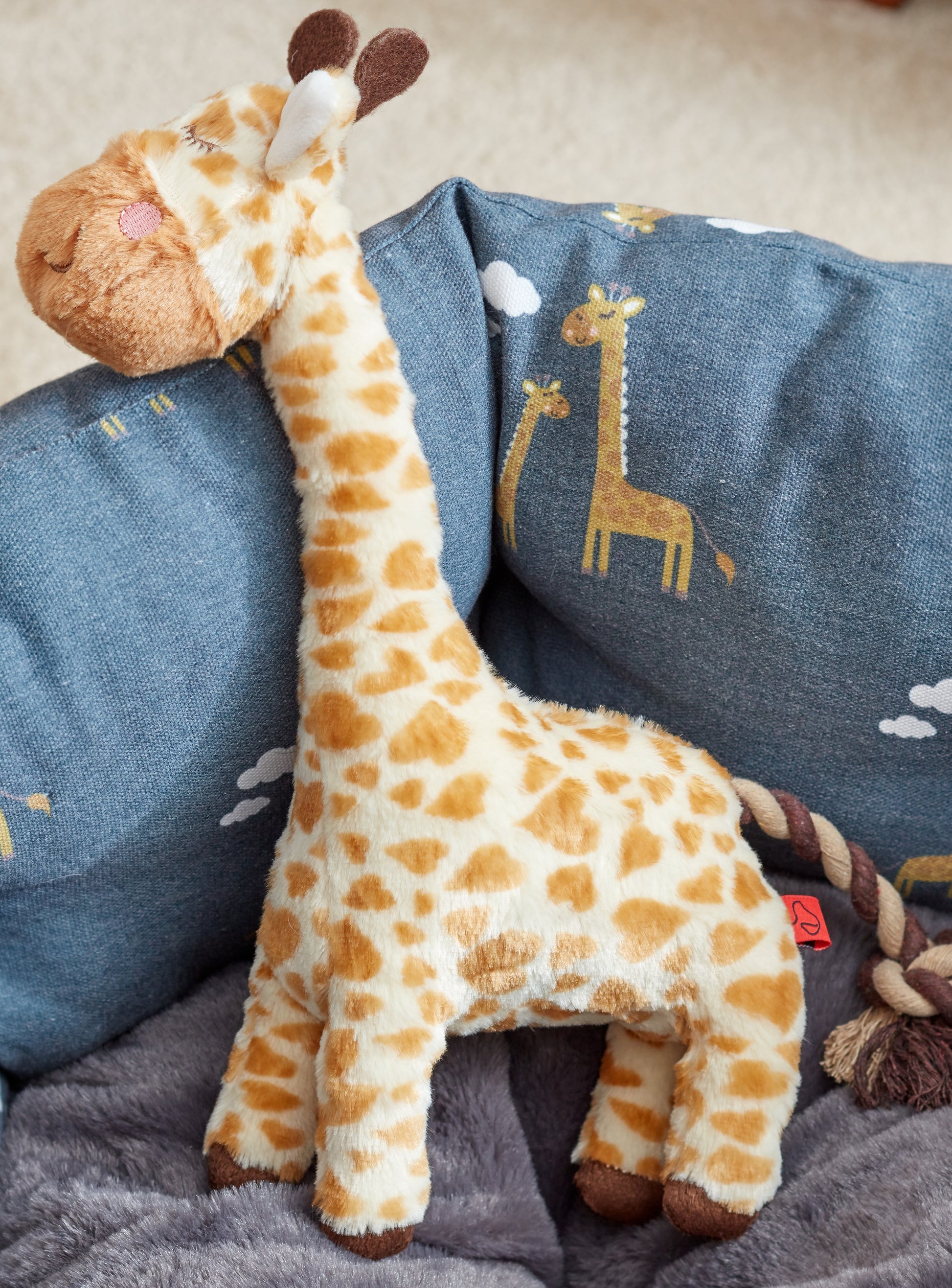 Plush giraffe toy on a blue blanket with giraffe designs