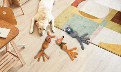 Dog lying on a wooden floor with colorful dog toys nearby