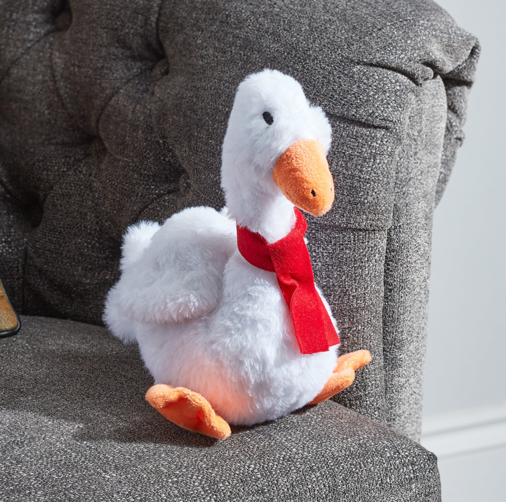 Plush duck toy with a red scarf on a gray textured surface
