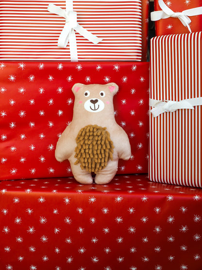 Teddy bear with a hedgehog plush toy on red gift wrap with white star pattern