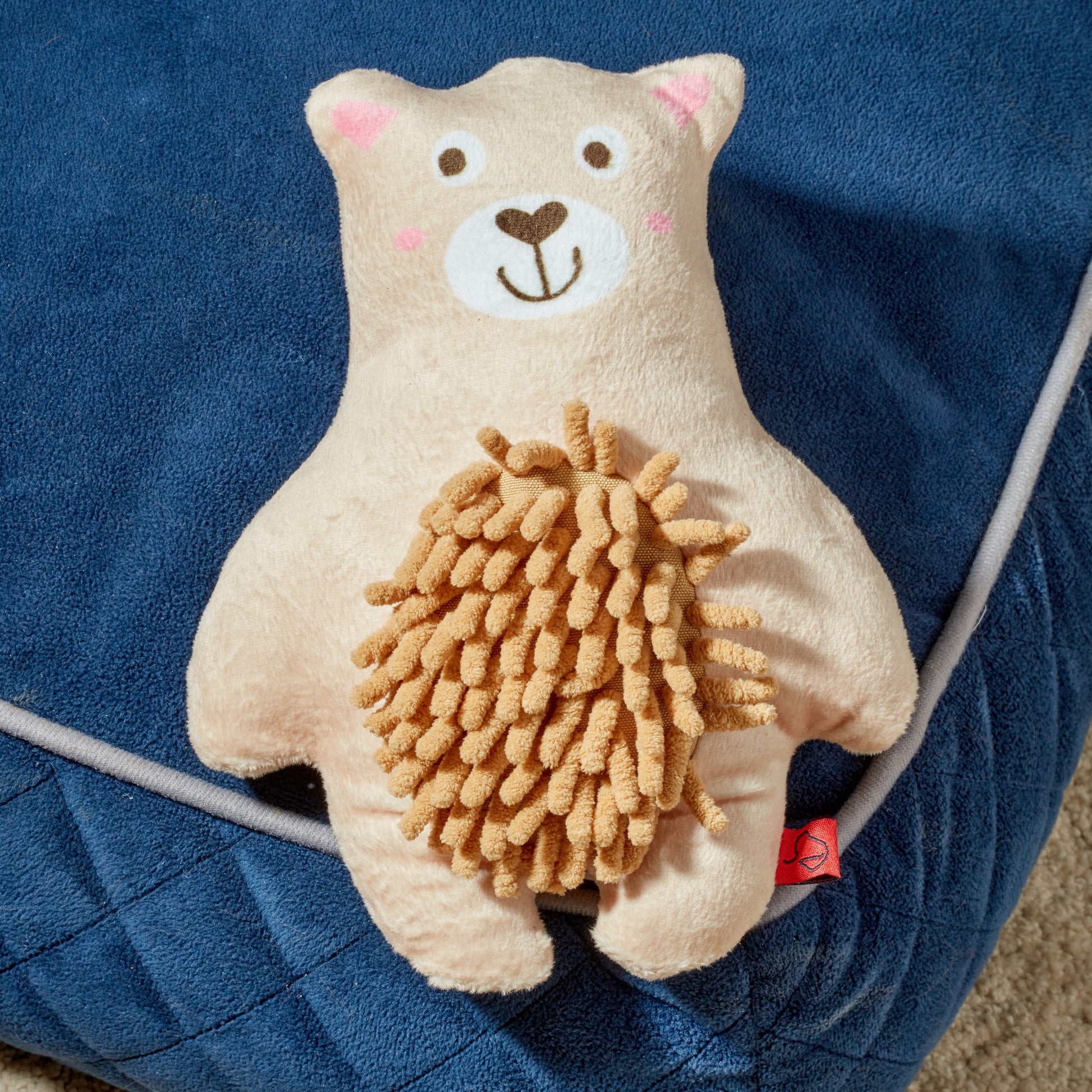 Plush toy bear with a lion's mane on a blue blanket
