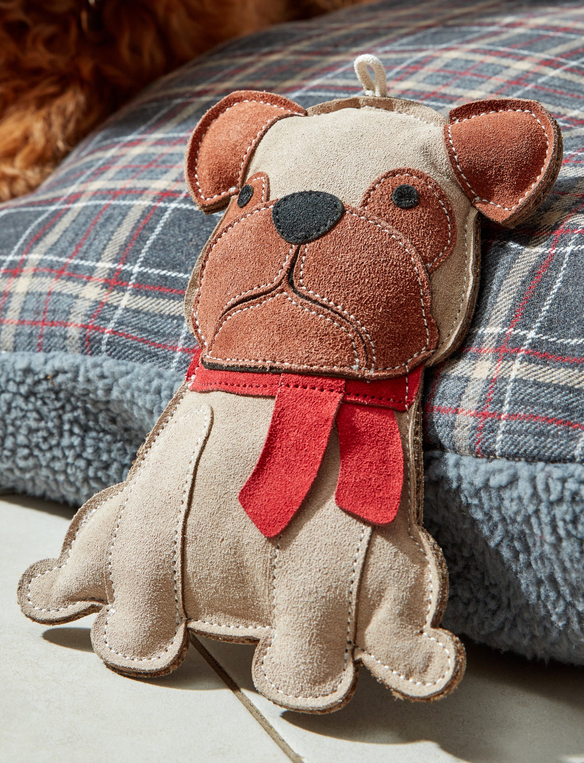 Stuffed dog toy with a red scarf on a plaid fabric background