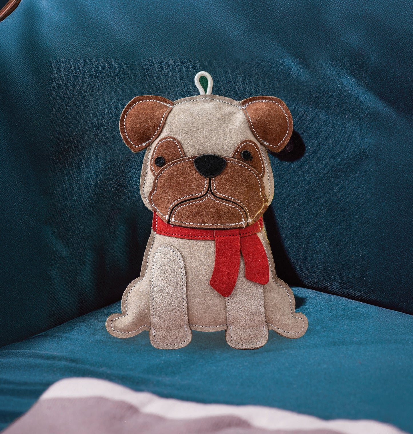 Stuffed dog toy with a red scarf on a blue cushion