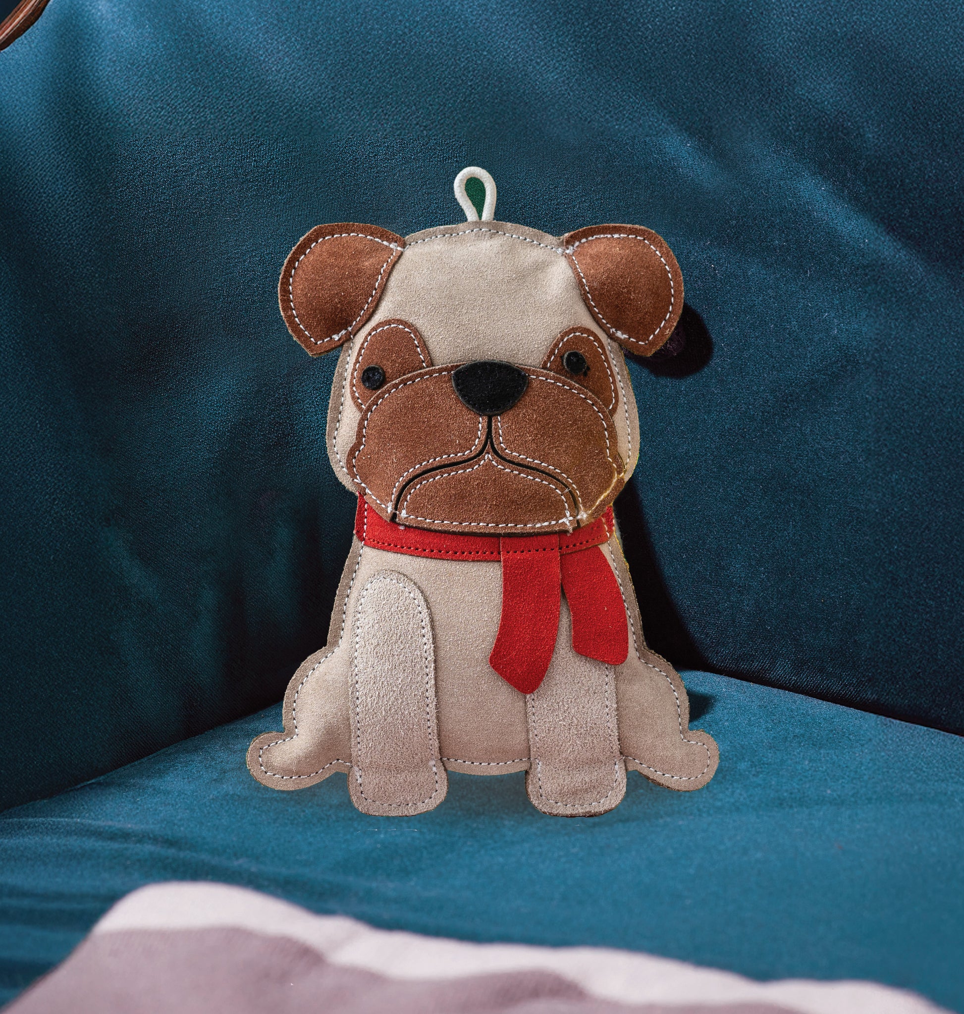 Stuffed dog toy with a red scarf on a blue cushion