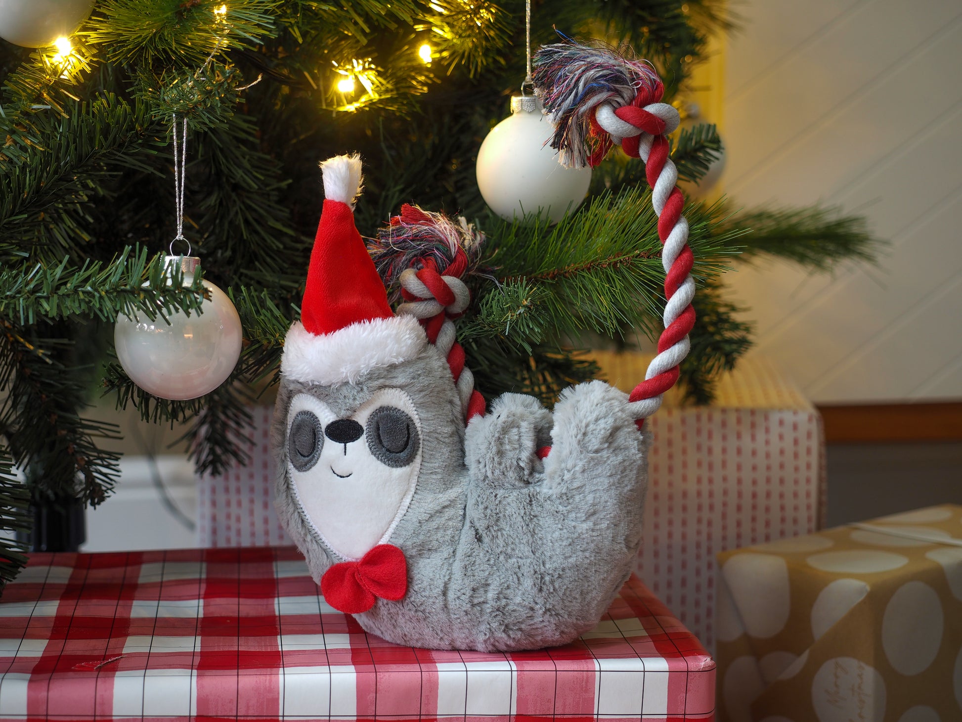 Decorative sloth ornament with a Santa hat on a Christmas tree branch.