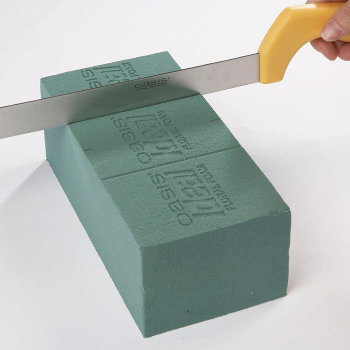 Green foam block with a knife cutting through it on a white background