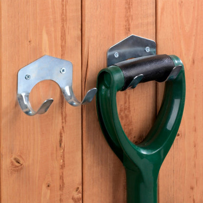 Green garden tool with metal wall hooks attached to a wooden wall