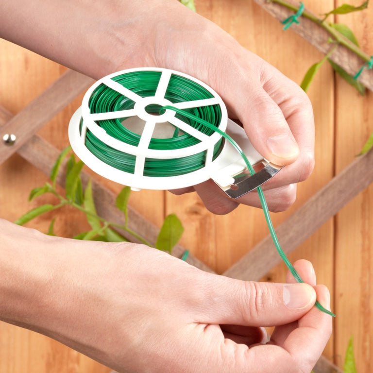 Person holding a spool of green wire with a wooden background