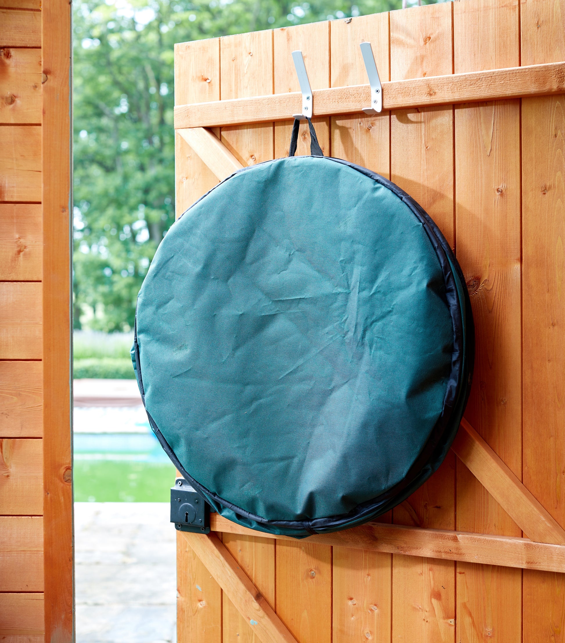 Green round bag hanging on a wooden fence