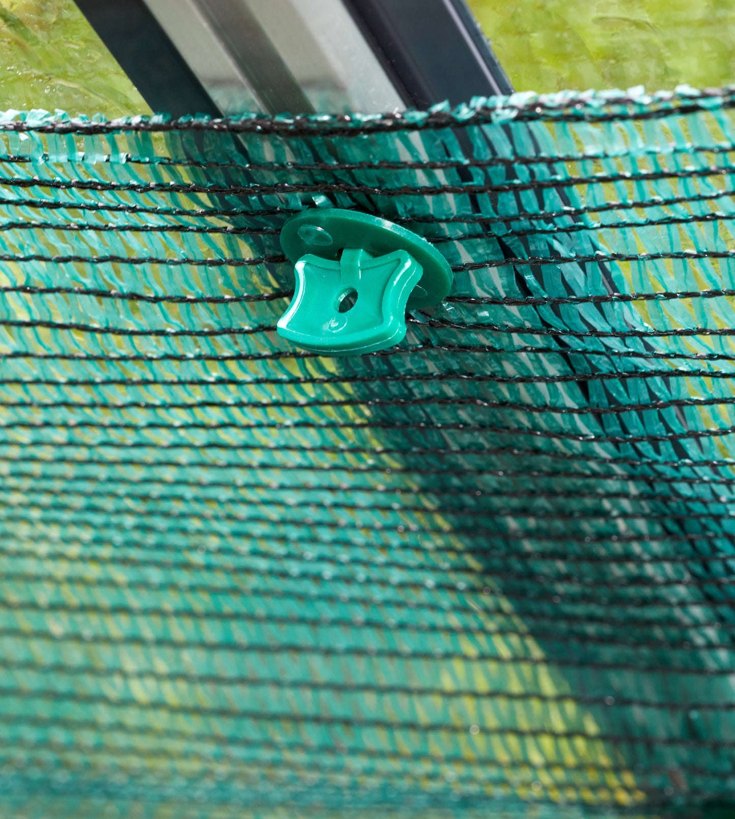 Close-up of a green mesh screen with a plastic clip on a grassy background