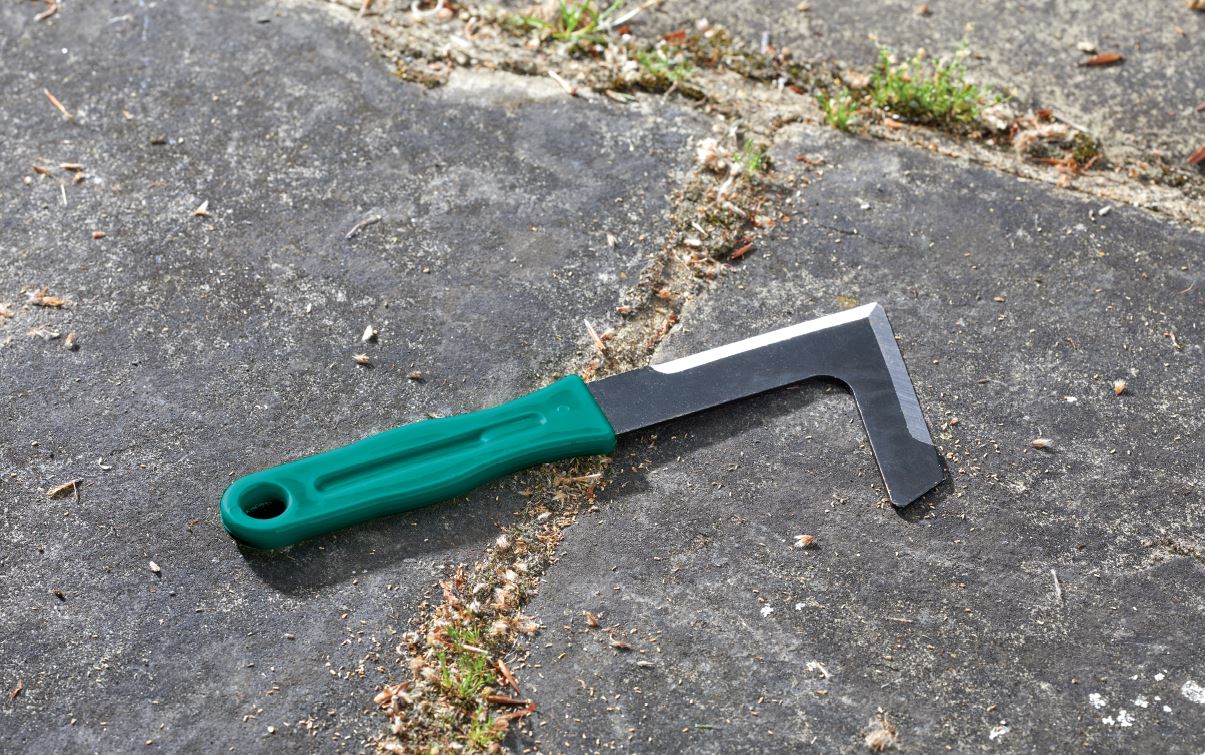 Green-handled scraper on a textured surface