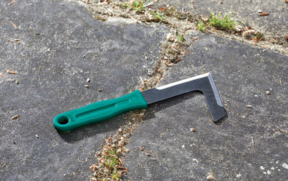 Green-handled scraper on a textured surface