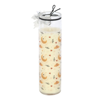 Tall glass candle with moon and leaf pattern on a white background