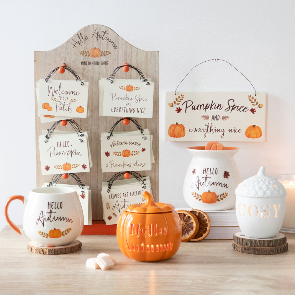 Autumn-themed decor items including mugs, a teapot, and signs on a wooden surface.