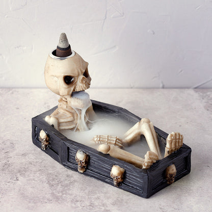 Decorative skeleton in a coffin with a skull on top against a light background