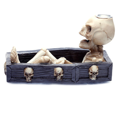 Decorative item with a skeleton in a coffin and a skull on top, on a white background