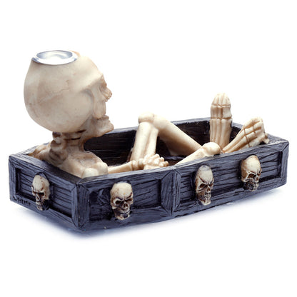 Decorative skeleton figure in a coffin with skulls on a white background