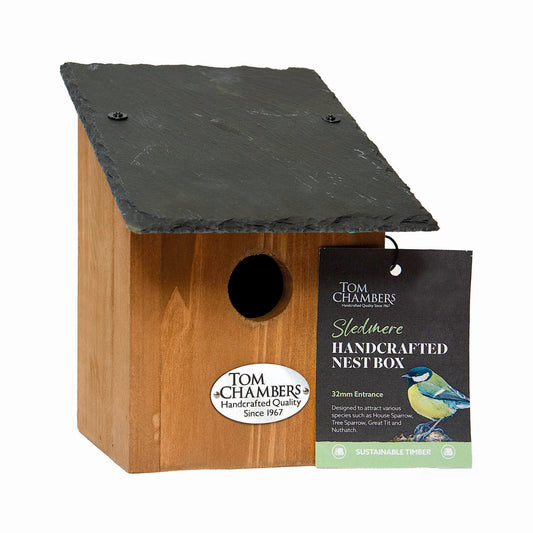 Wooden birdhouse with green roof and Tom Chambers packaging on a white background