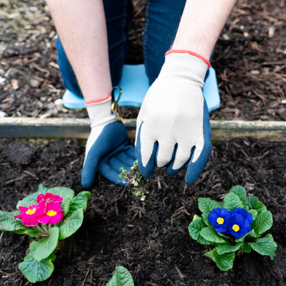 Person planting flowers in a garden with gardening gloves on
