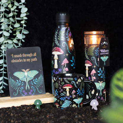Set of decorative items including a water bottle, mug, and candle with mushroom and butterfly designs on a dark background.
