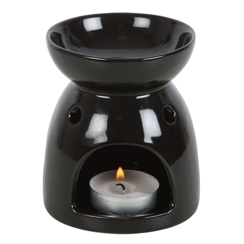 Black ceramic oil burner with a lit candle inside on a white background