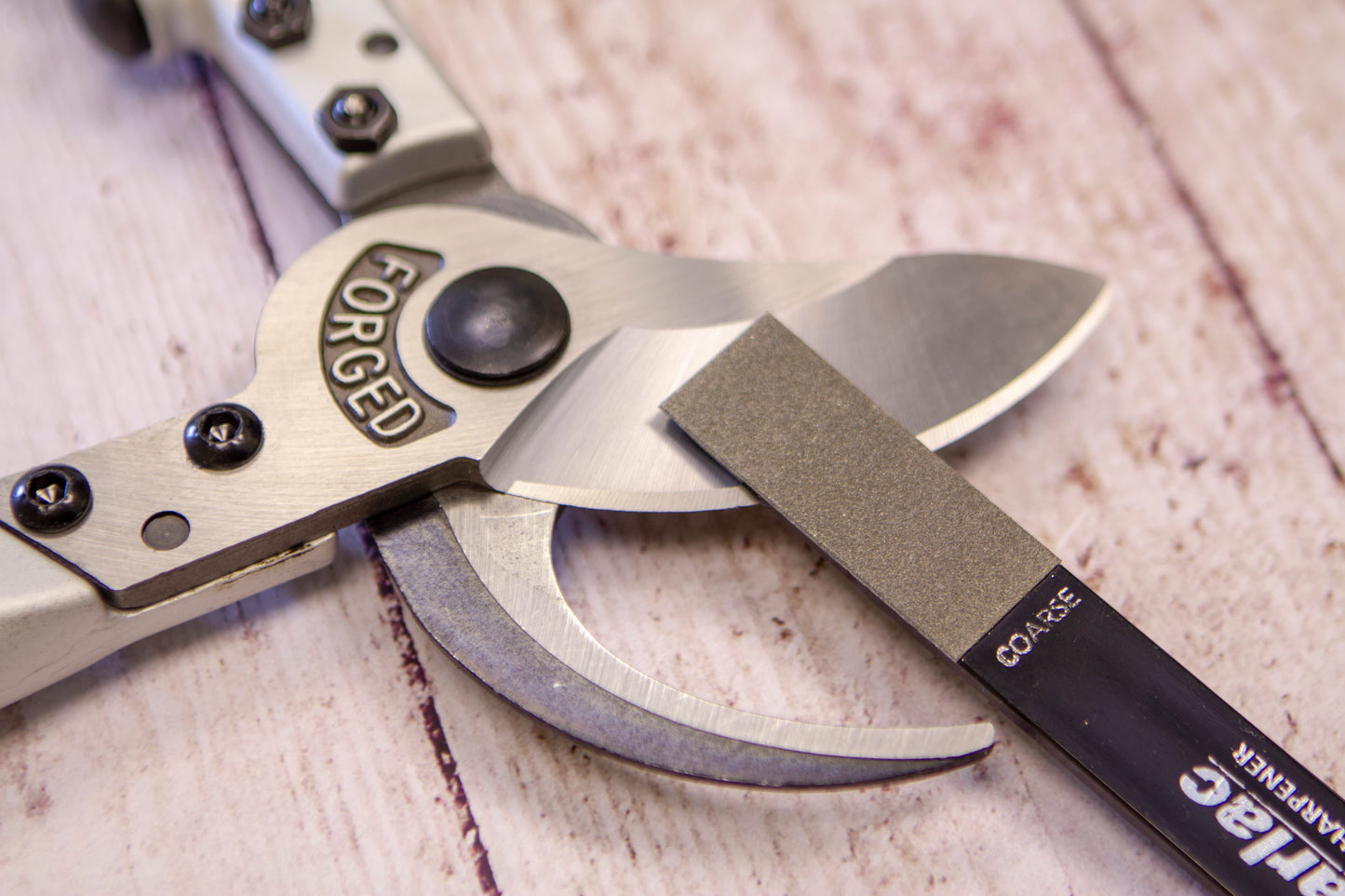 Pair of garden shears with 'Forged' branding on a wooden surface