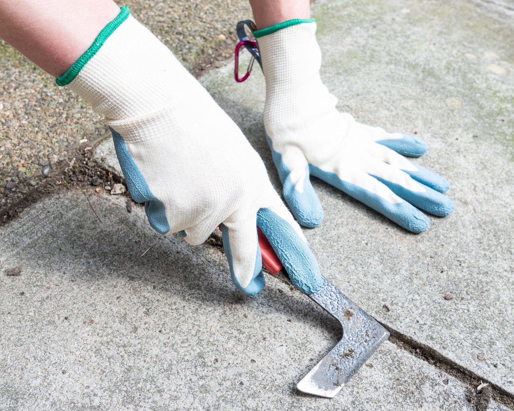 Person wearing gloves using a tool on a concrete surface