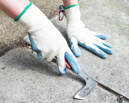 Person wearing gloves using a tool on a concrete surface