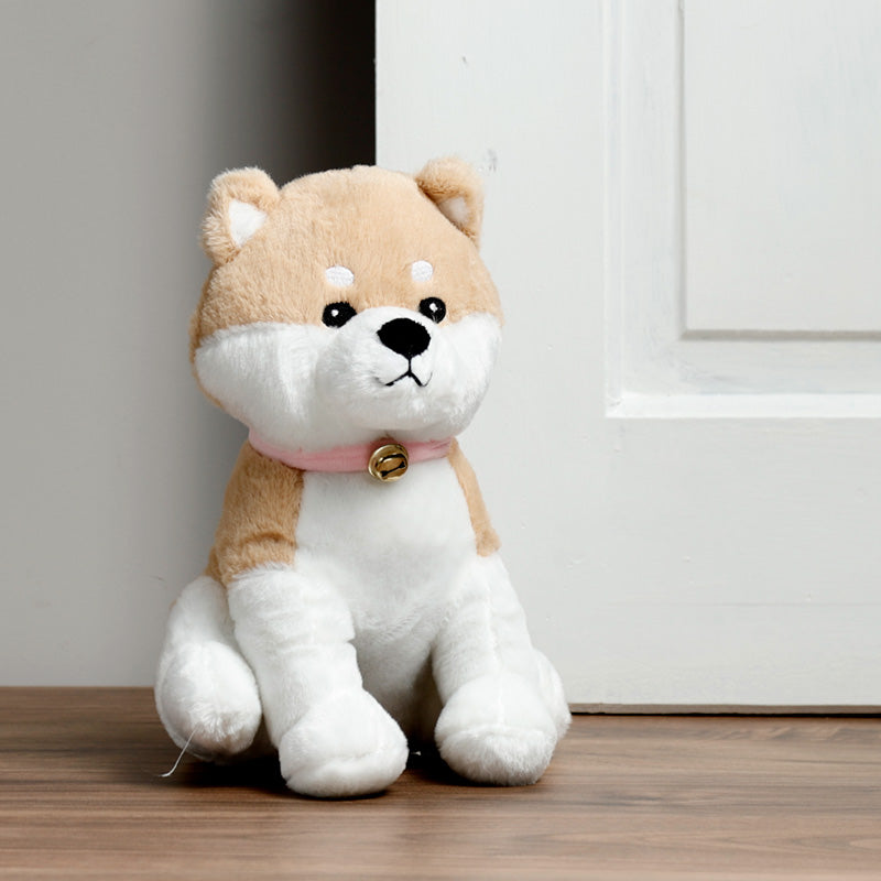 Plush toy dog with a pink collar in front of a door