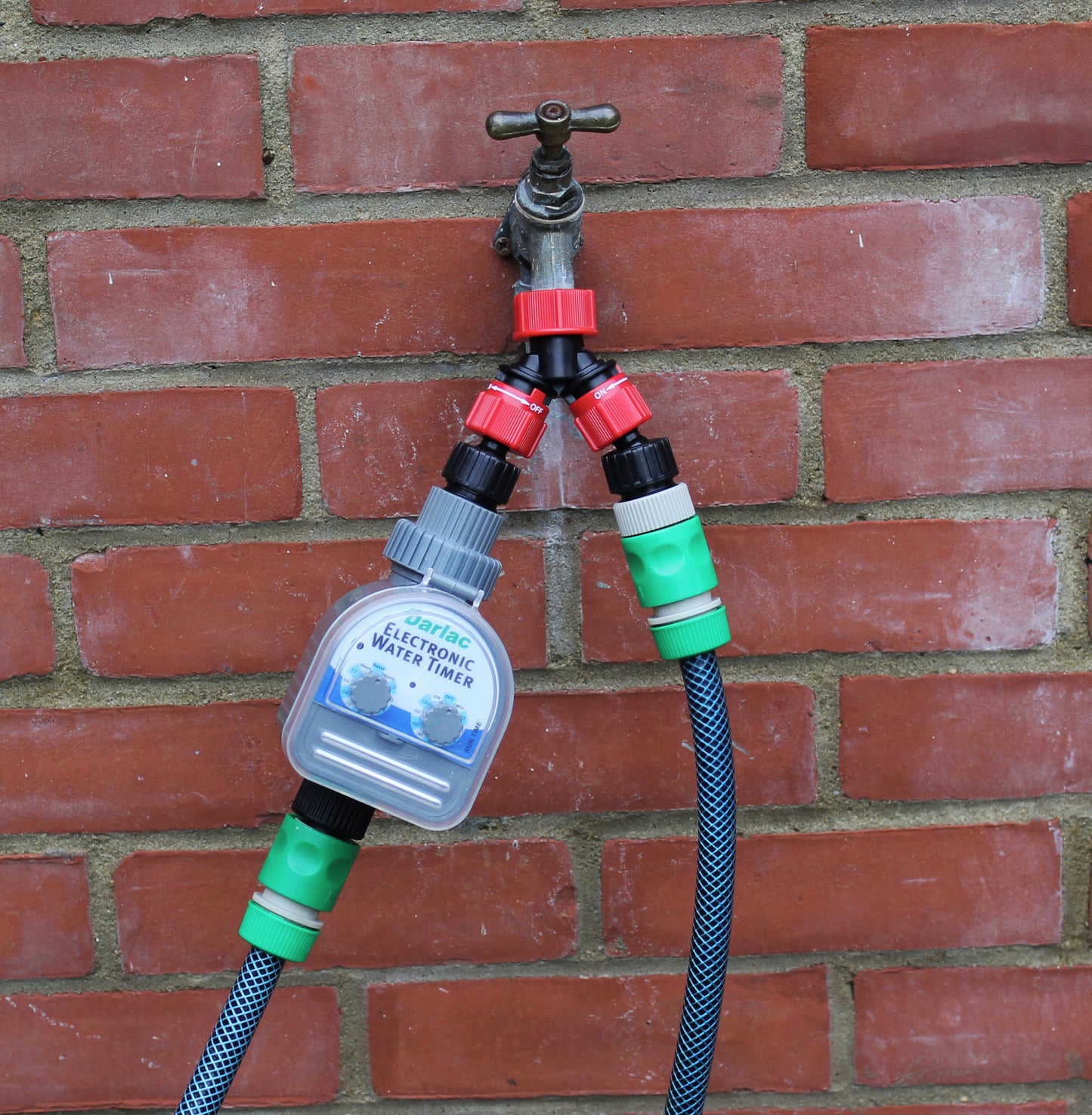 Garden hose with multiple connectors against a brick wall