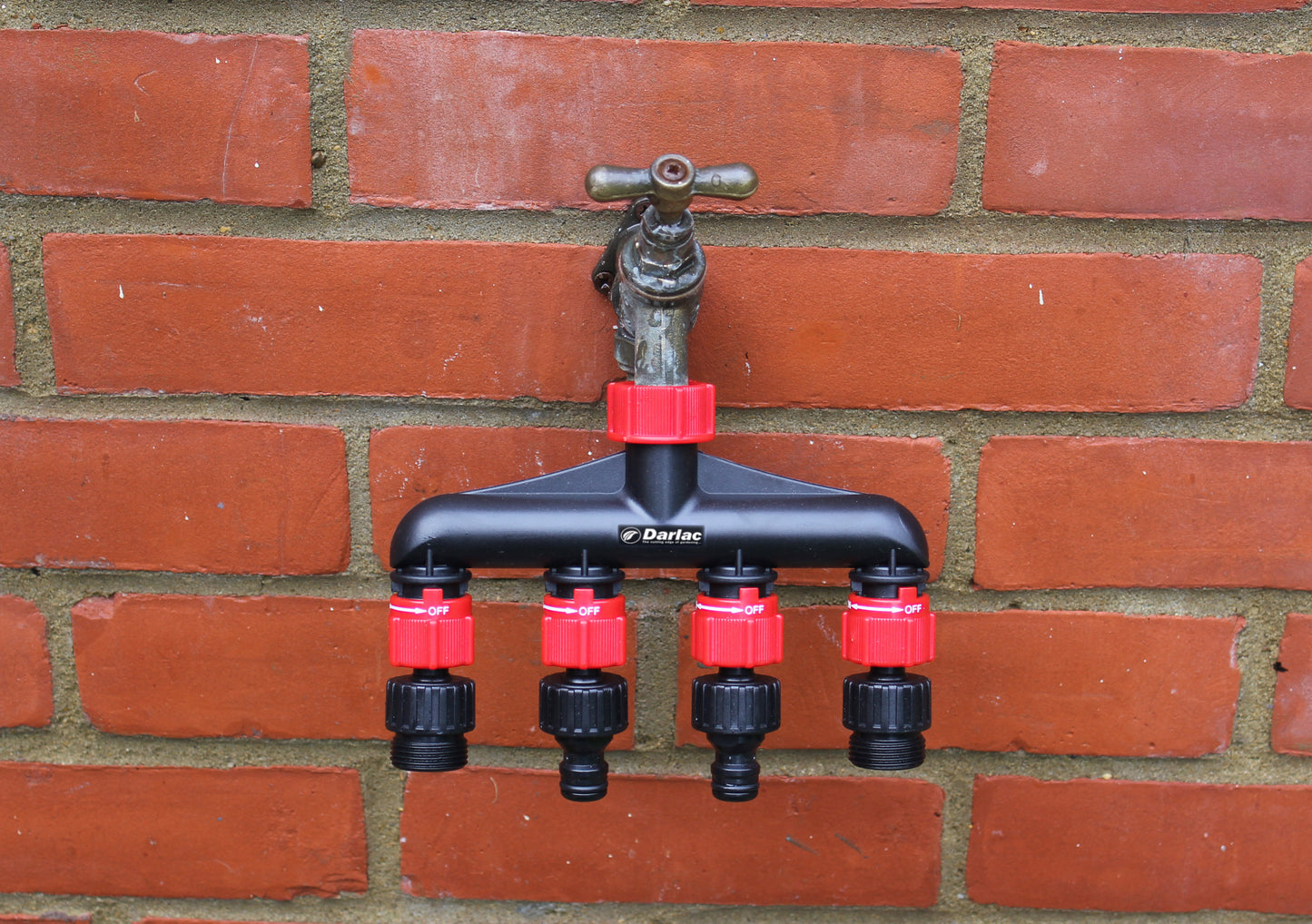 Garden irrigation valve system attached to a brick wall