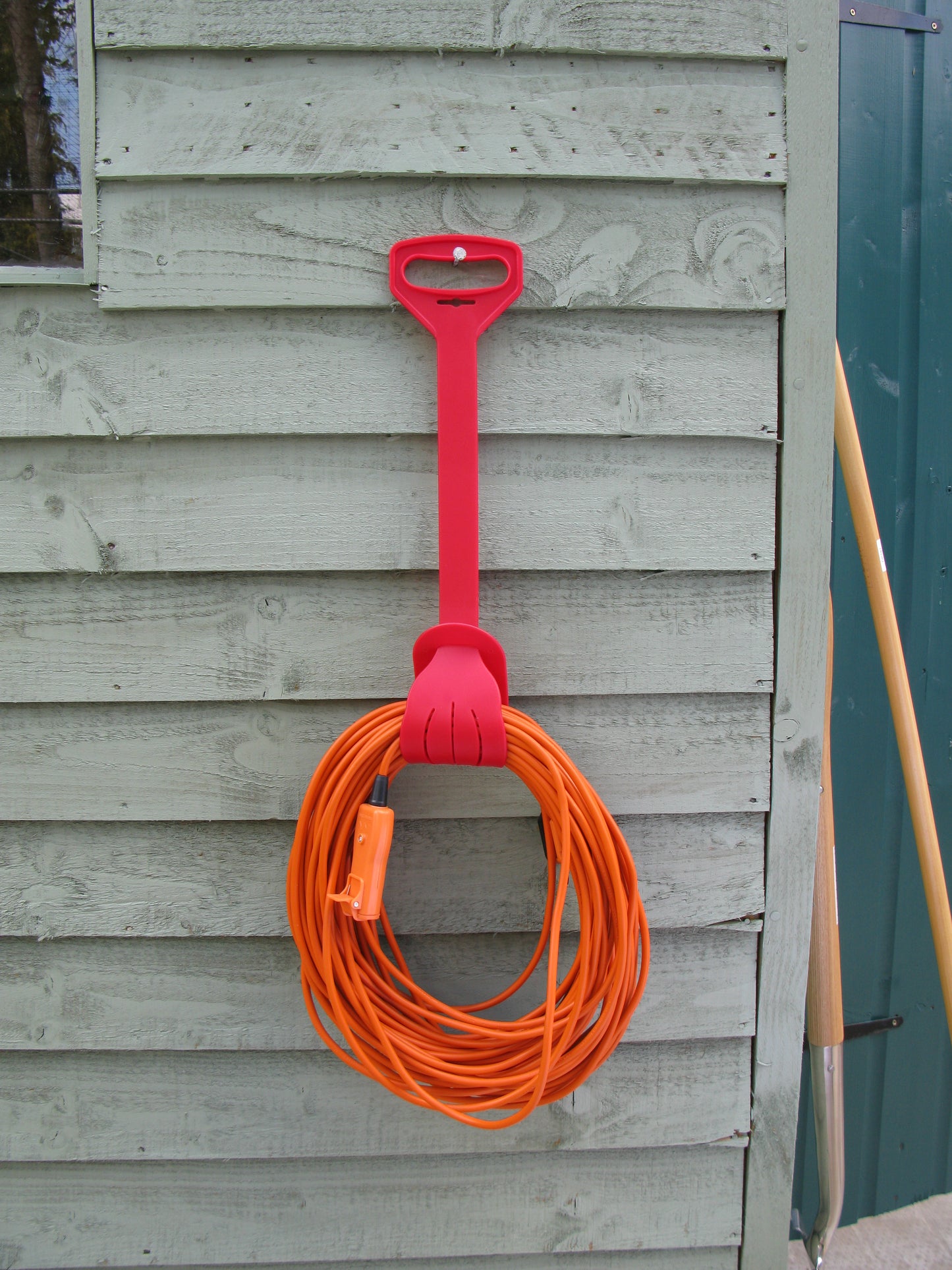 Red hose holder with orange hose attached to a wooden wall