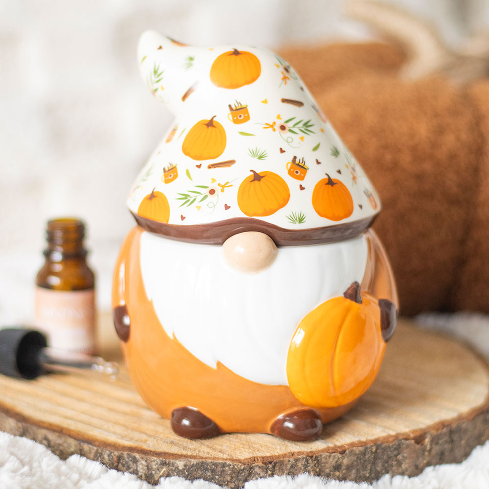 Decorative gnome with pumpkin design on hat, sitting on a wooden surface.