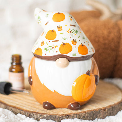 Decorative gnome with pumpkin design on hat, sitting on a wooden surface.