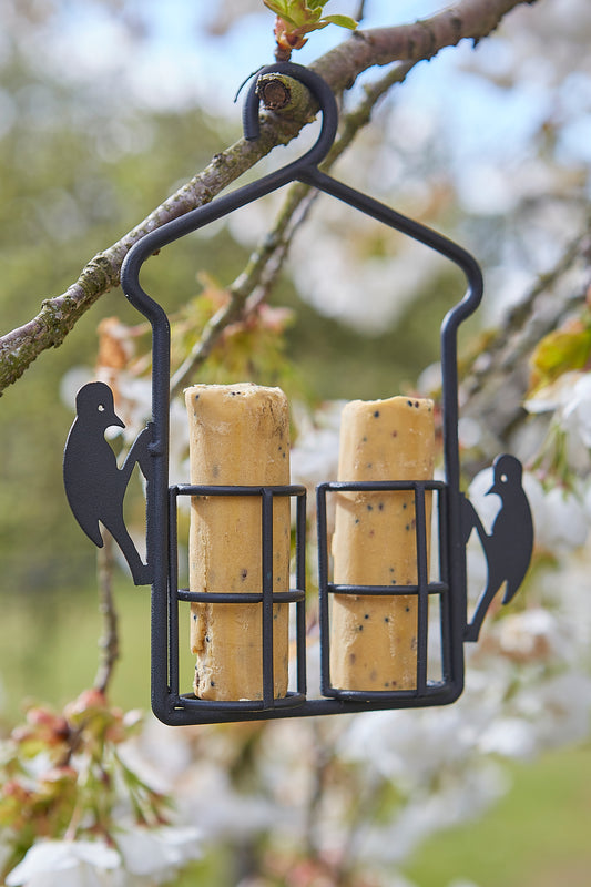 Wine cork feeder with two corks hanging from a branch with blurred floral background