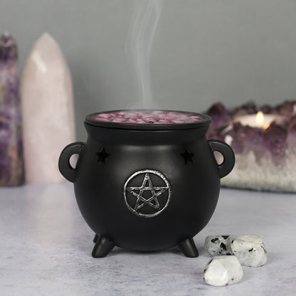 Black cauldron with a pentagram design, incense burning inside, on a neutral background with crystals.