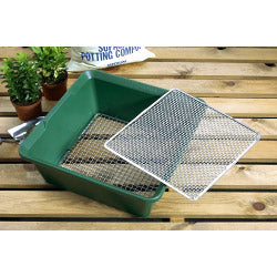 Green potting compost container with a metal sieve on a wooden surface