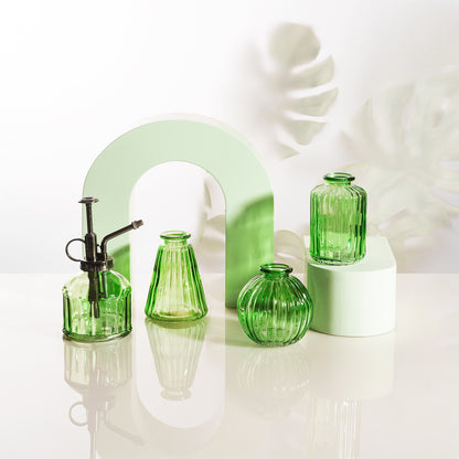 Green glass vases on a white surface with a light green arch in the background